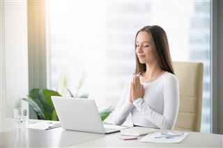 Young woman meditating near laptop