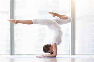 Young attractive woman in handstand exercise