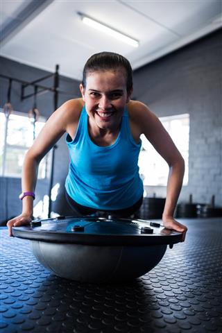 Smiling athlete with BOSU ball in gym