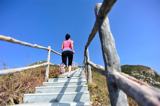 Woman running up on mountain stairs