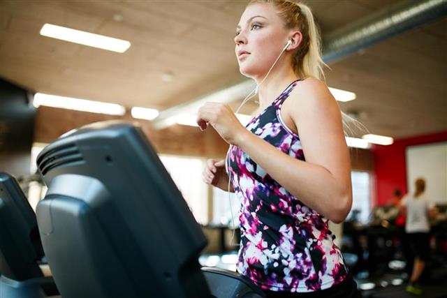 Fit woman running on treadmill in gym