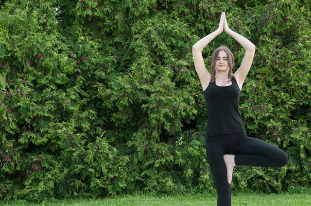 Beautiful young woman doing yoga in a park outside