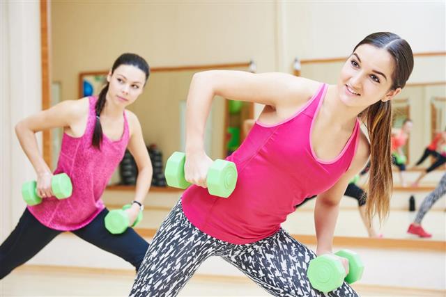 Young fitness woman with dumbbell in gym
