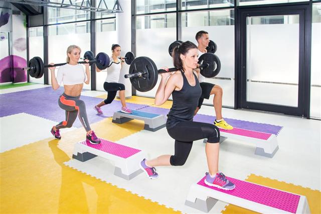 Group of sporty people lifting barbells at gym