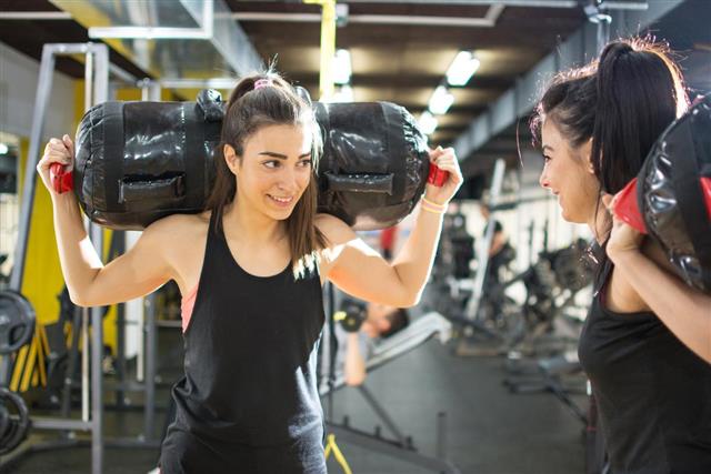 Sporty women carrying on fitness bags on shoulders at gym