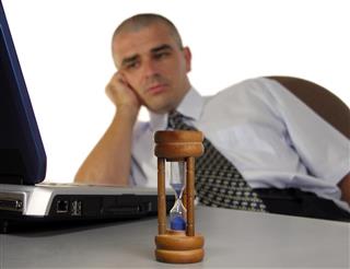 Tired Businessman Behind Hourglass
