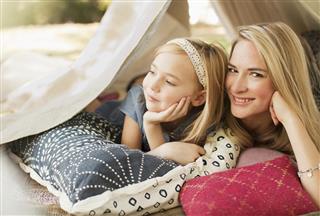Mother and daughter laying in tent outdoors
