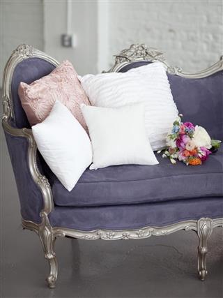 Purple couch with pillows and floral bouquet
