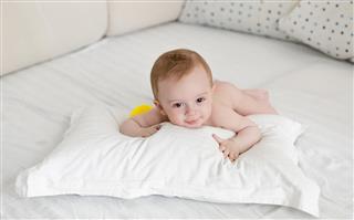 Adorable baby boy relaxing on pillow after bathing