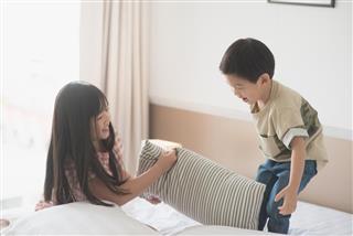 Asian child having Pillow Fight in Hotel Room