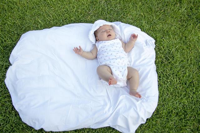 Sleeping baby lying on pillow on the grass in park