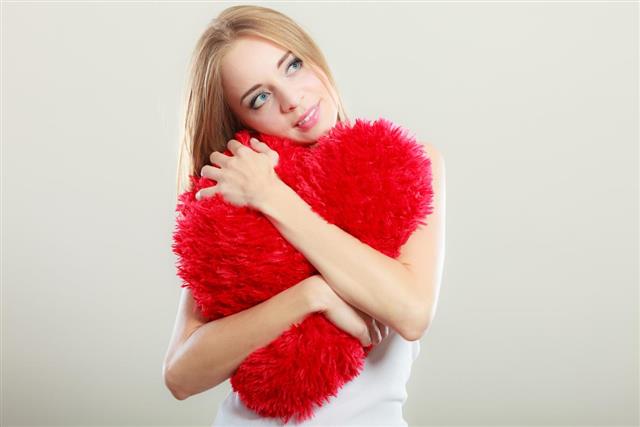 Woman holding heart shaped pillow love symbol