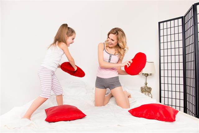 Mother and her daughter fighting with pillows