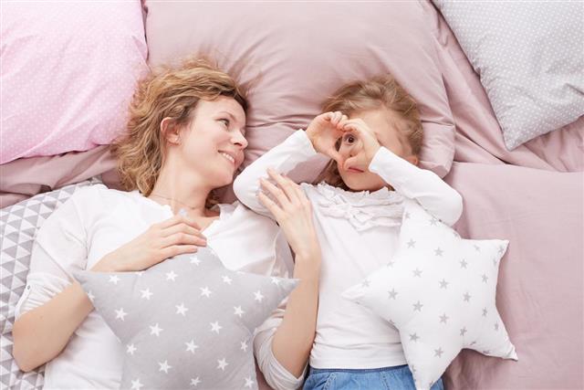 Mom and daughter laying on a bed