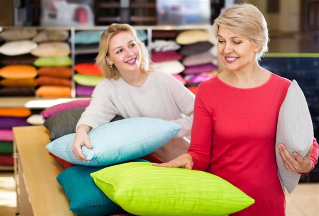 Attentive young and senior female customers looking through pillows in textile shop