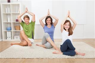 Family Practicing Yoga On Rug