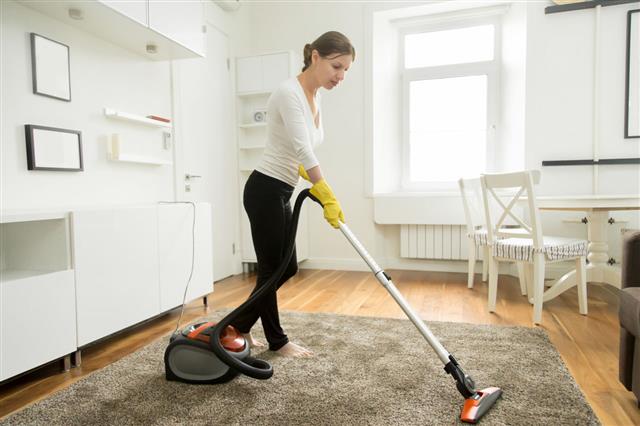 Woman Vacuum Cleaning The Carpet