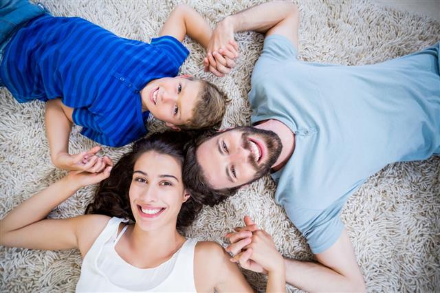 Parents And Son Lying On Rug