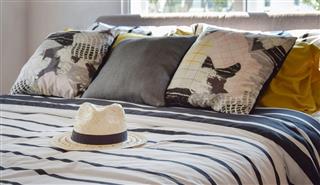 Antique straw hat on black and white patterned bed