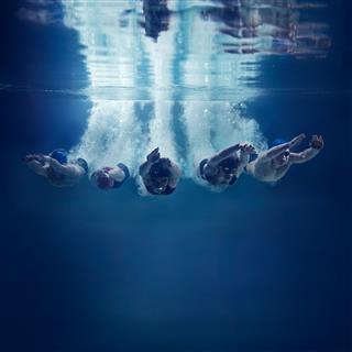 Swimmers Jumping Together Into Water