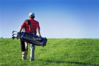 Male Golfer Carrying Bag Of Clubs