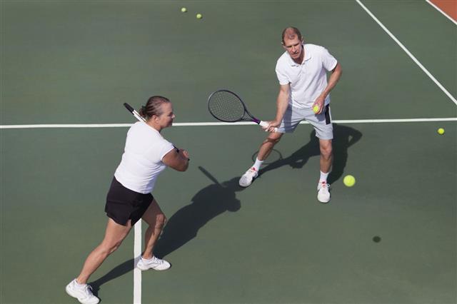 Older Couple Playing Tennis On Court