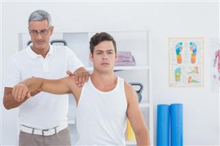 Doctor Stretching A Young Man Arm