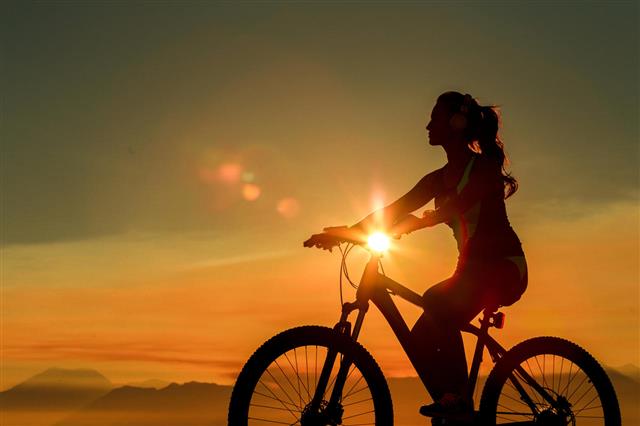Sporty Woman Riding Bicycle On Sunset