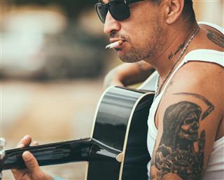 Tattooed man playing guitar