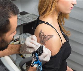 Artist making tattoo on arm