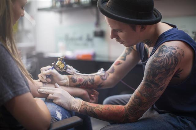 Artist making tattoo on hand
