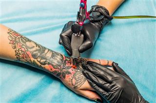 Artist making tattoo on hand