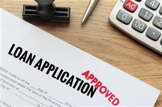 Approved loan application with rubber stamp and calculator