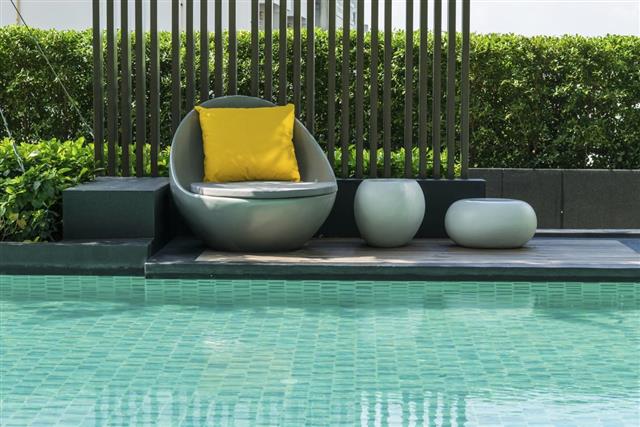 Relaxing chairs with pillows beside swimming pool
