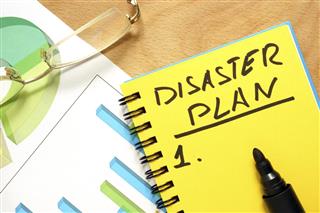 Notepad with disaster plan on a wooden table