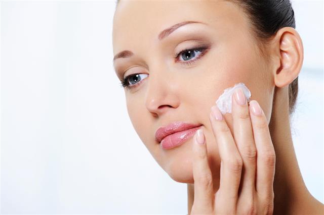 Woman caring of her face with moisturizer cream