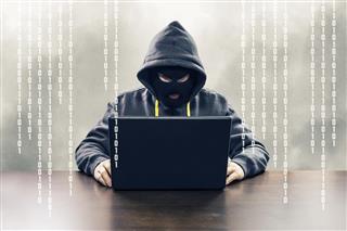 Masked computer hacker attacking internet services