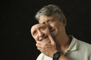 Bipolar disorder depressed man removing his mask of happiness