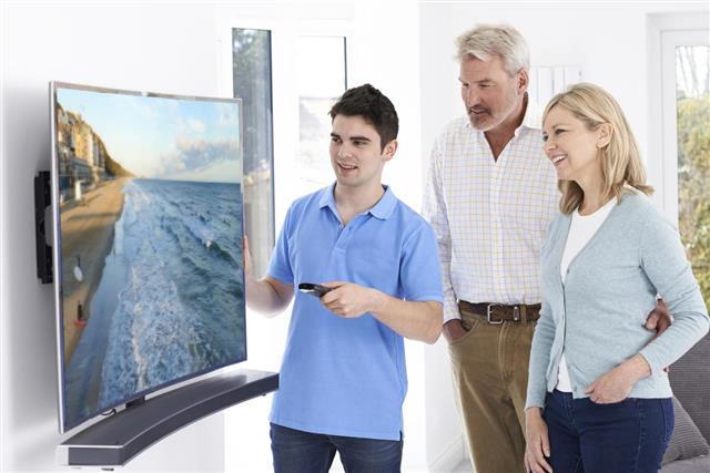Man Demonstrating New Television To Mature Couple At Home