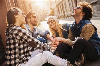 Photo of laughing friends joining hands outdoors