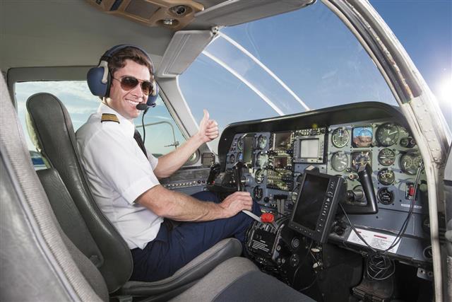 Young pilot in aircraft cockpit giving thumbs up