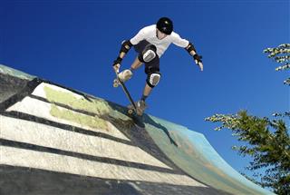 A skateboarder wearing gear in action on an outdoor ramp