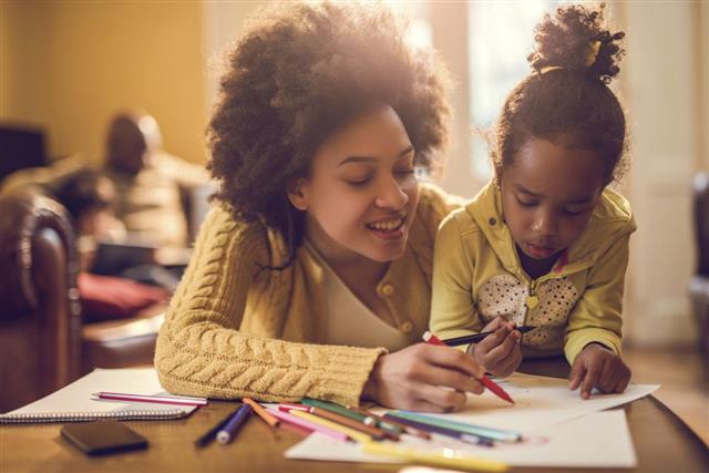 Happy African American mother assisting her daughter in coloring