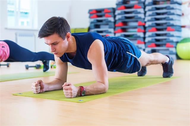 Fitness training athletic sporty man doing plank exercise in gym
