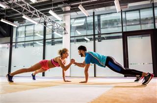 Smiling couple doing push-ups together in a gym
