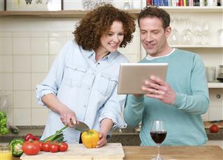 Happy man and woman looking at tablet in the kitchen