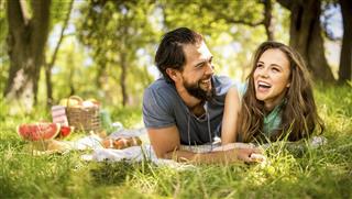 Laughing girl and her boyfriend relaxing at a park picnic