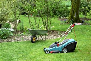 Electric Lawn Mower and Wheelbarrow in a Garden