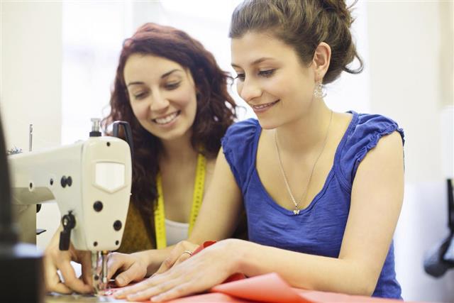 Fashion designer sewing fabrics with assistant