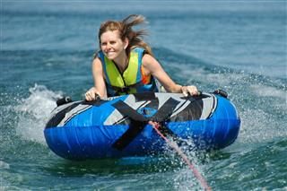 Young Adult Female Inner Tubing Behind Speedboat